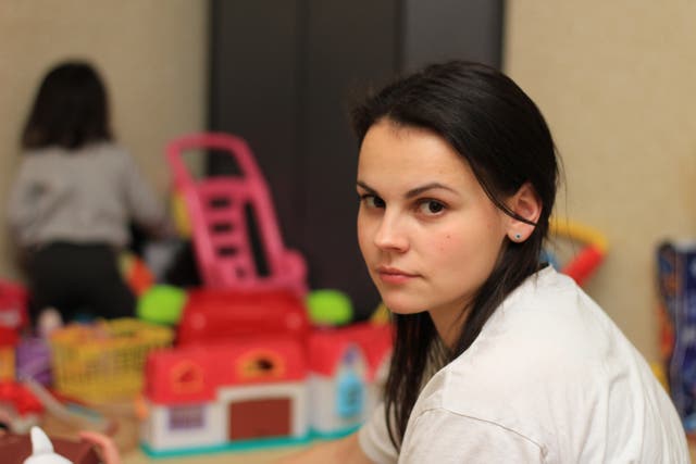 Young mum looking towards the camera as child plays in background