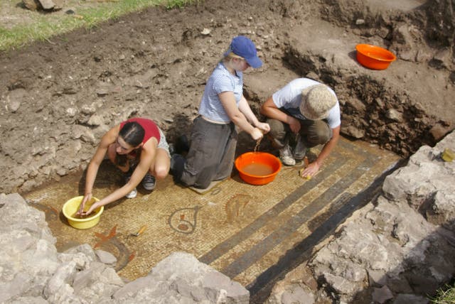 <p>Archaeologists cleaning a rare 2,000-year-old mosaic depicting dolphins </p>