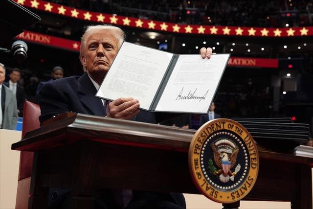 <p>President Donald Trump signs an executive order as he attends an indoor Presidential Inauguration parade event at Capital One Arena</p>