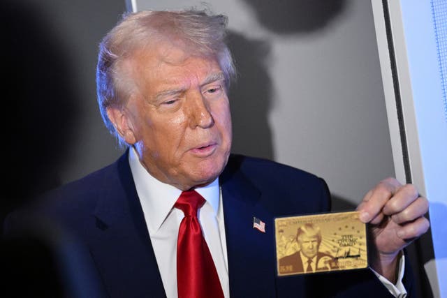 <p>Donald Trump holds up the $5 million gold card that grants U.S. residency to wealthy immigrants as he speaks to reporters Thursday on board Air Force One, en route to Miami</p>