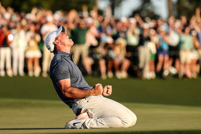 <p>McIlroy sinks to his knees after holing the putt that secured the Masters title, and his career grand slam, at Augusta on Sunday</p>