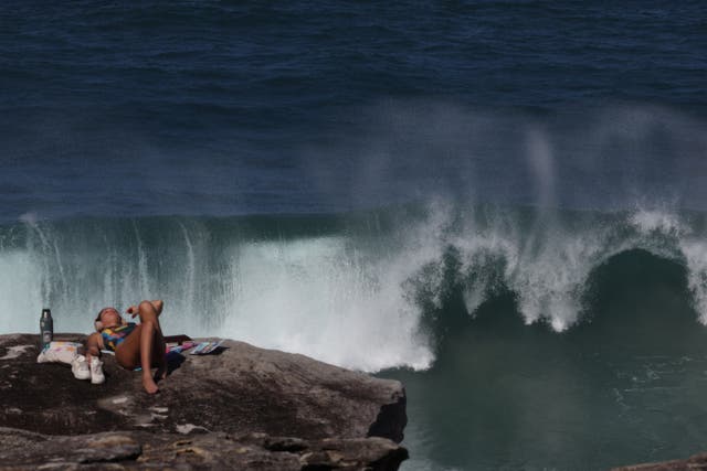 <p>A tourist enjoys a sunny morning at Tamarama Beach as large waves crash against a rock in Sydney </p>