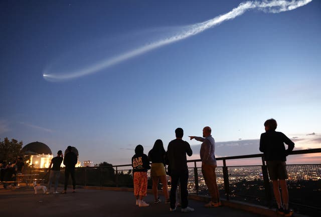 <p>People stand at Griffith Observatory as they view a SpaceX Falcon 9 rocket carrying a payload of 22 Starlink internet satellites into space, after launching from Vandenberg Space Force Base, on March 18, 2024 as seen from Los Angeles, California.</p>