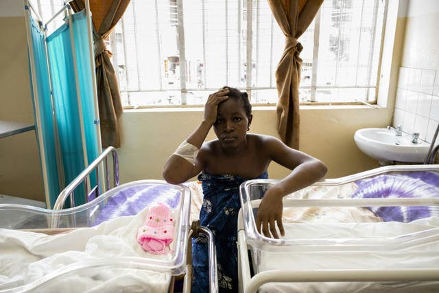 <p>A young mother of twins waits for her children to receive vaccinations in Freetown, Sierra Leone, which has one of the highest maternal mortality rates in the world</p>